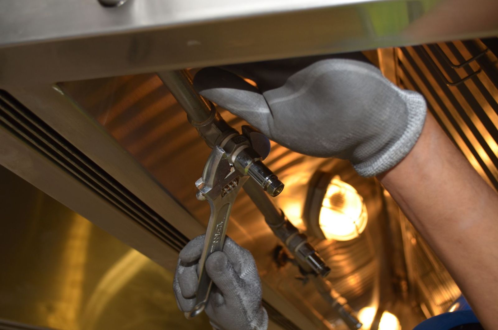 A worker tightening a pipe fitting with a wrench