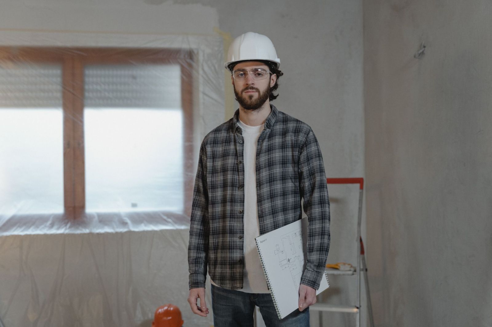 A construction worker holding printed plans at a renovation site