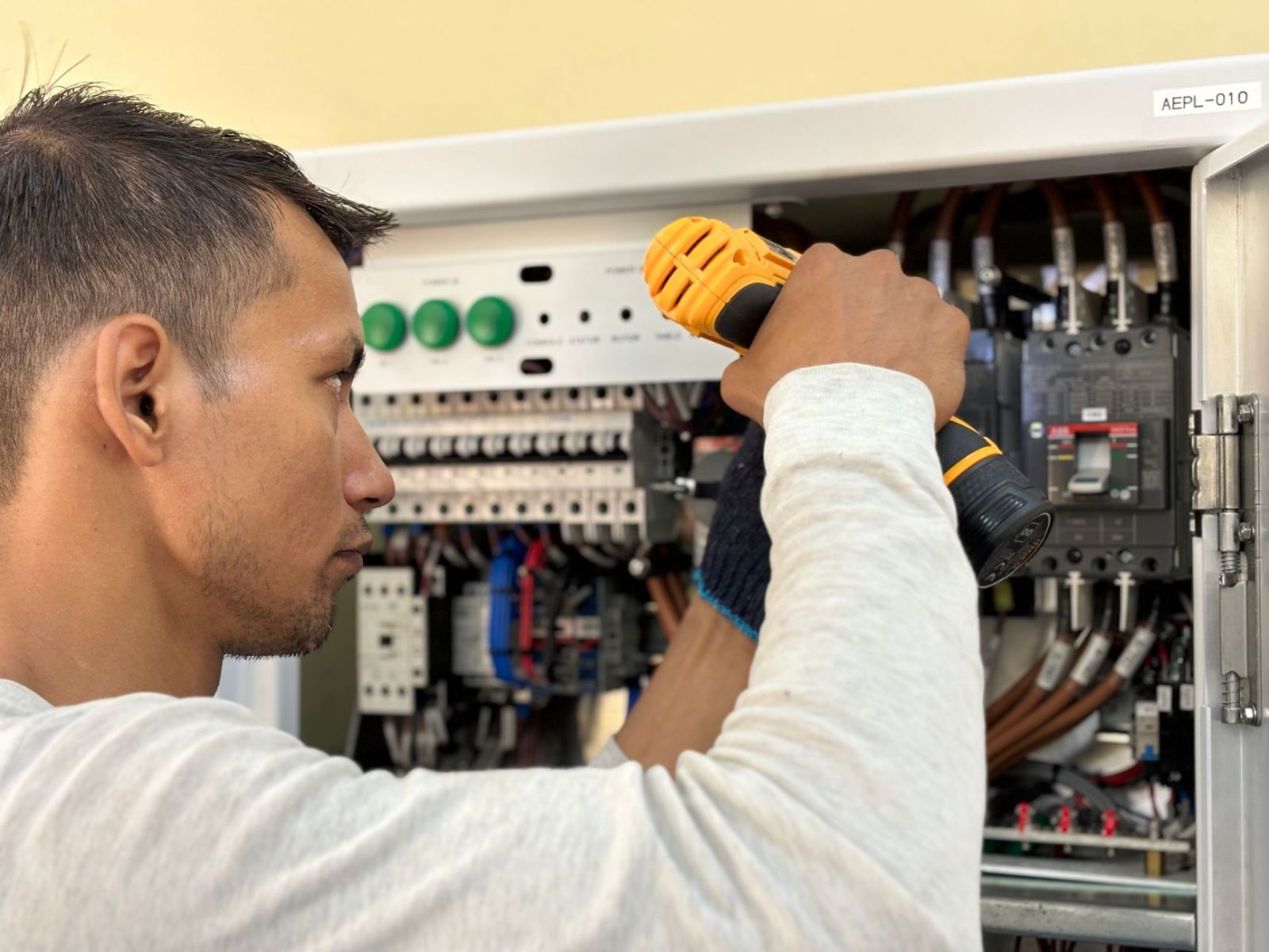 An electrician drilling inside a circuit breaker panel