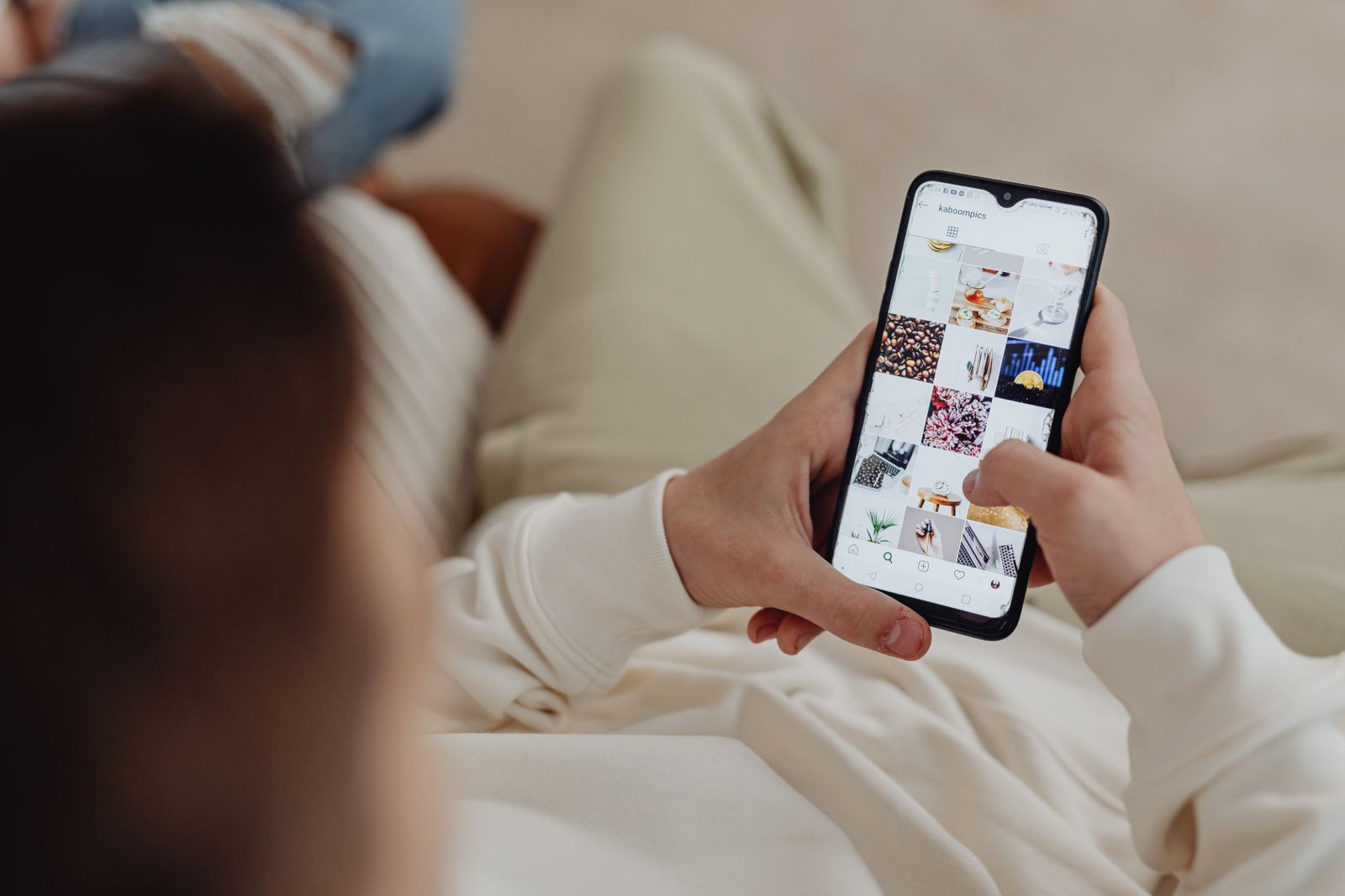 A person on a sofa scrolling through photos on a smartphone