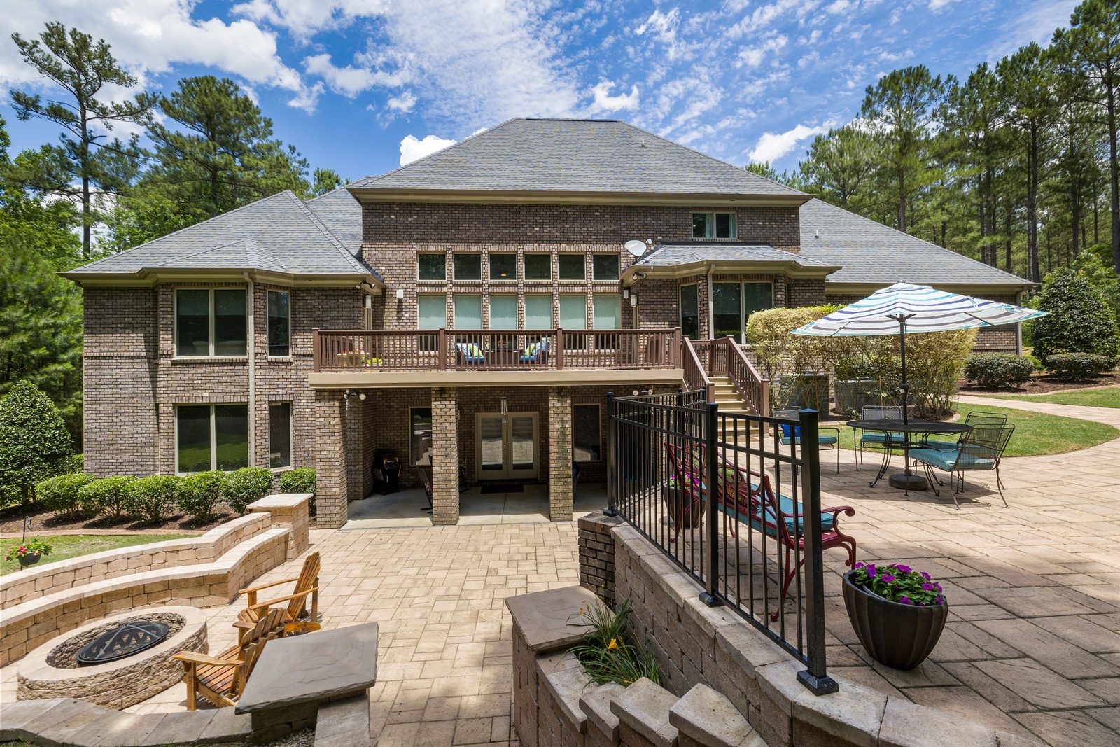 A brick house with a raised terrace, stone patio, fire pit and planted beds in the backyard
