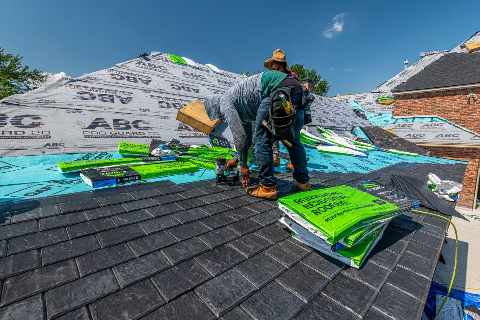 Workers installing a slate roof on a brick house in Fort Worth, Texas